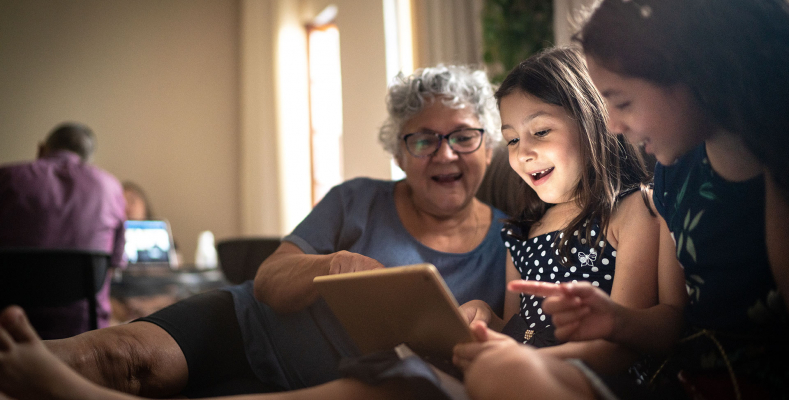 Grandma with granddaughters looking at tablet