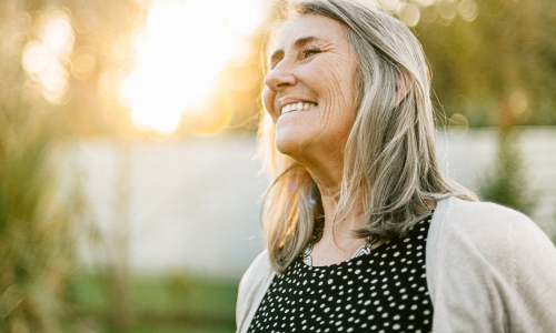 senior woman smiling in sunshine outdoors