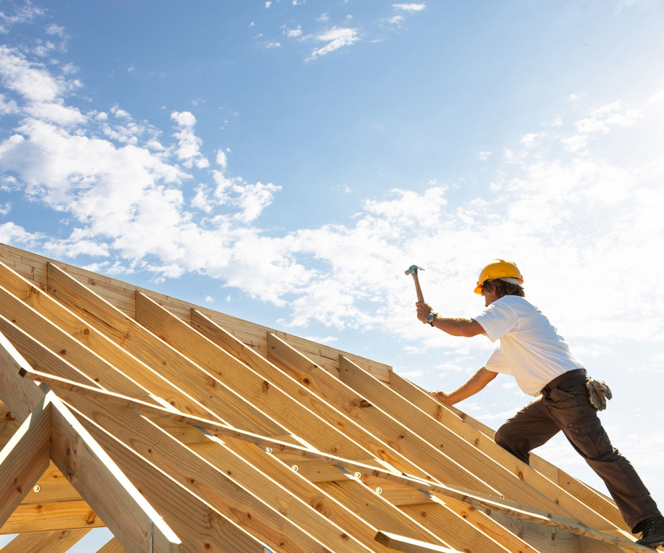 Construction worker building roof on house