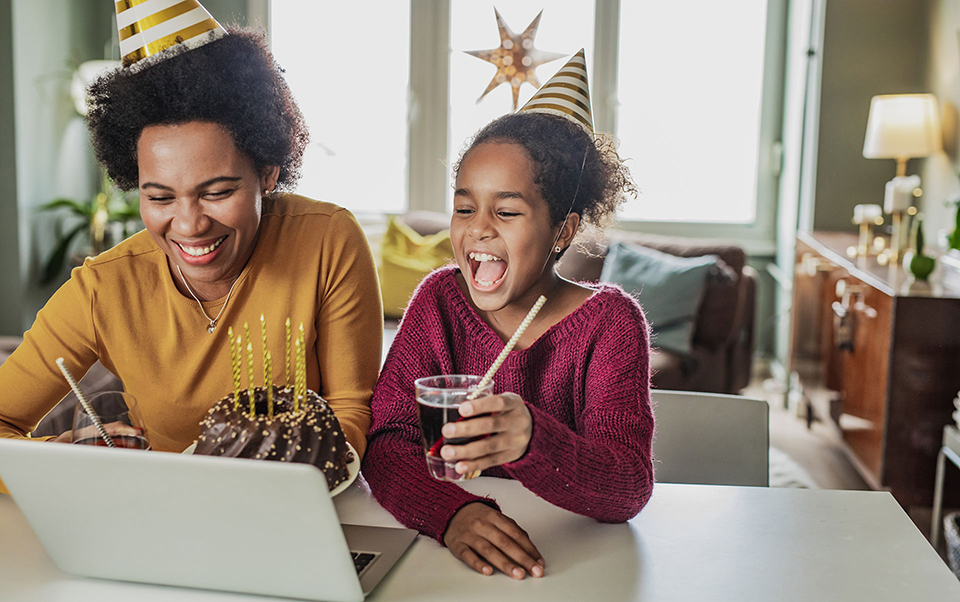 mother and daughter with birthday hats on a laptop
