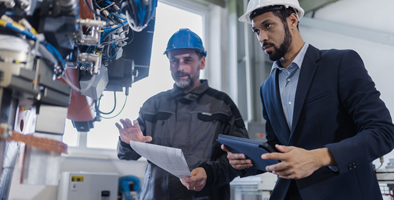 An engineering manager and mechanic worker doing routine check up in industrial factory